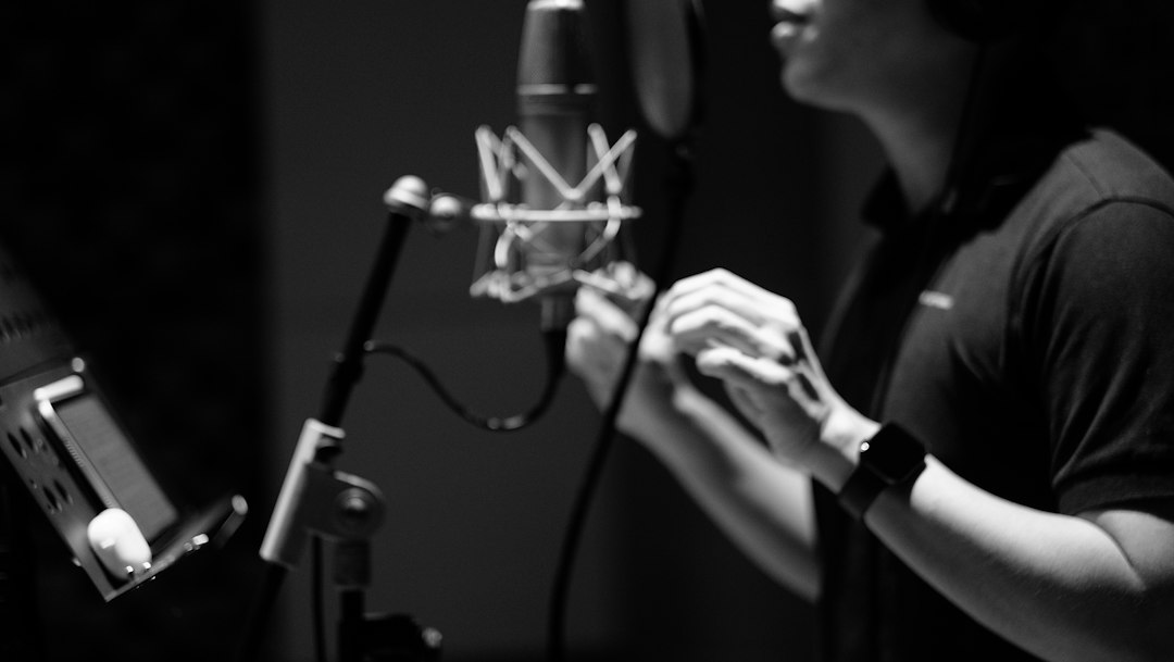 Podcaster speaking into a professional studio microphone to record a podcast promo