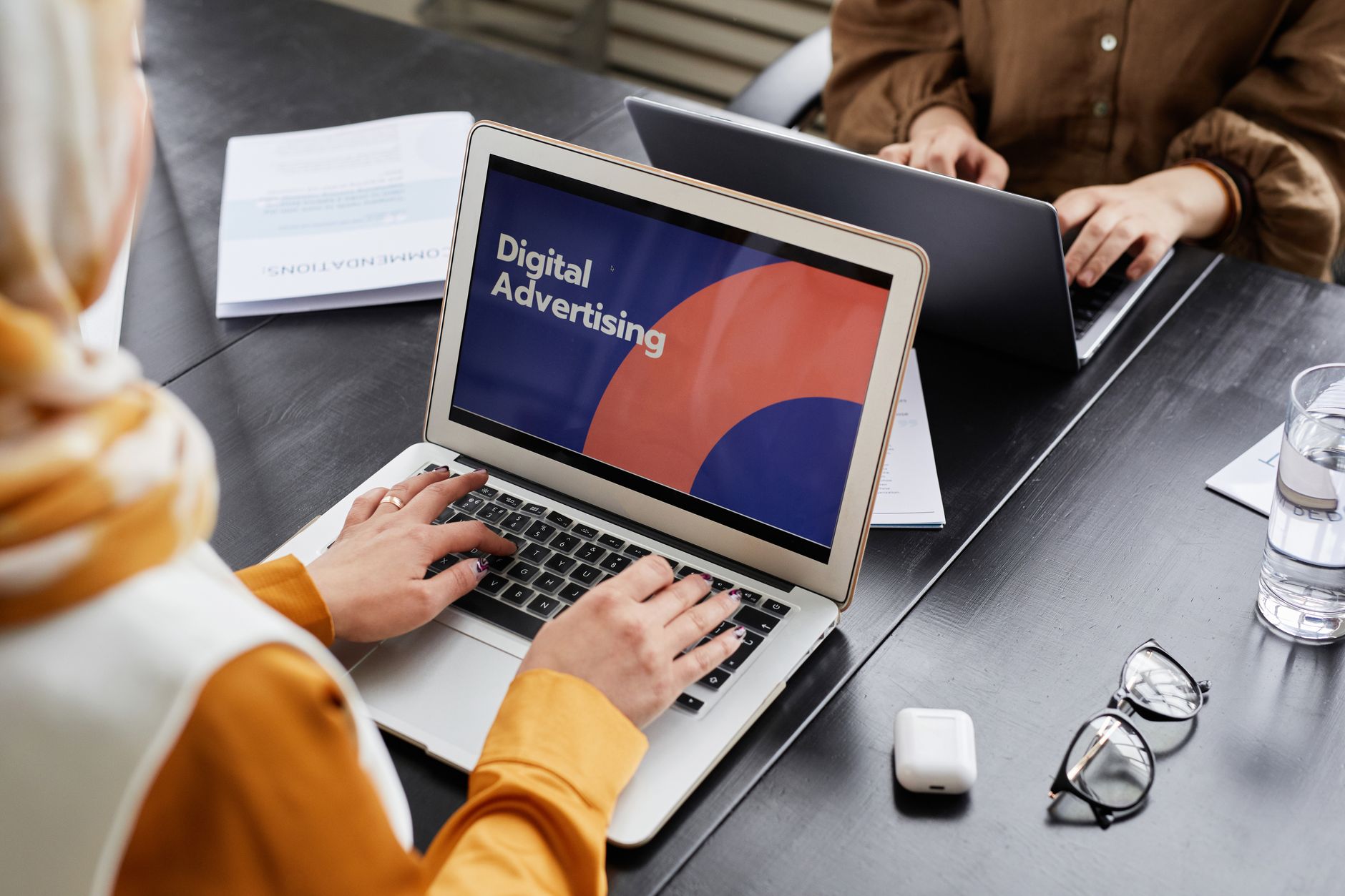 A person types on a laptop displaying a digital advertising slide