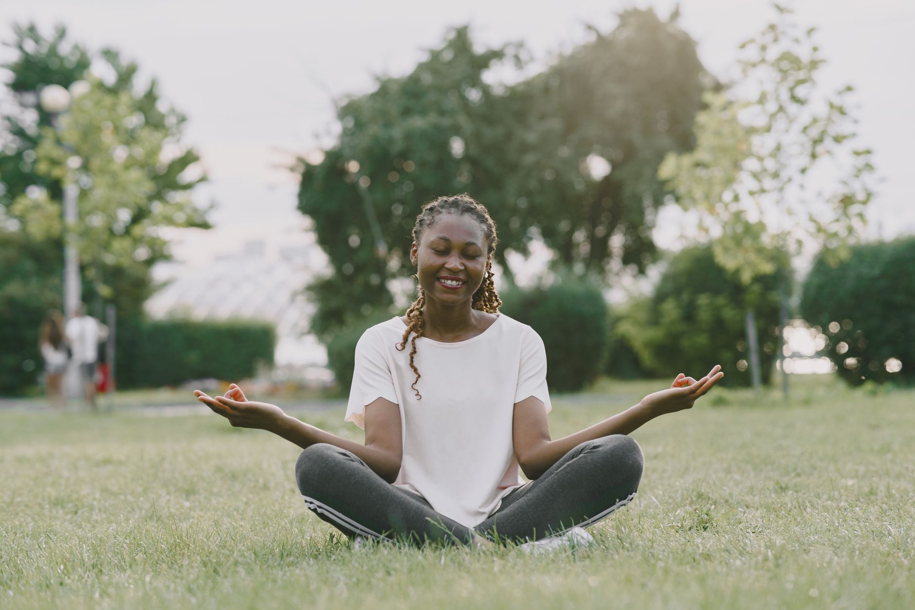 Smiling woman meditating outdoors, symbolizing nervous system regulation and peace
