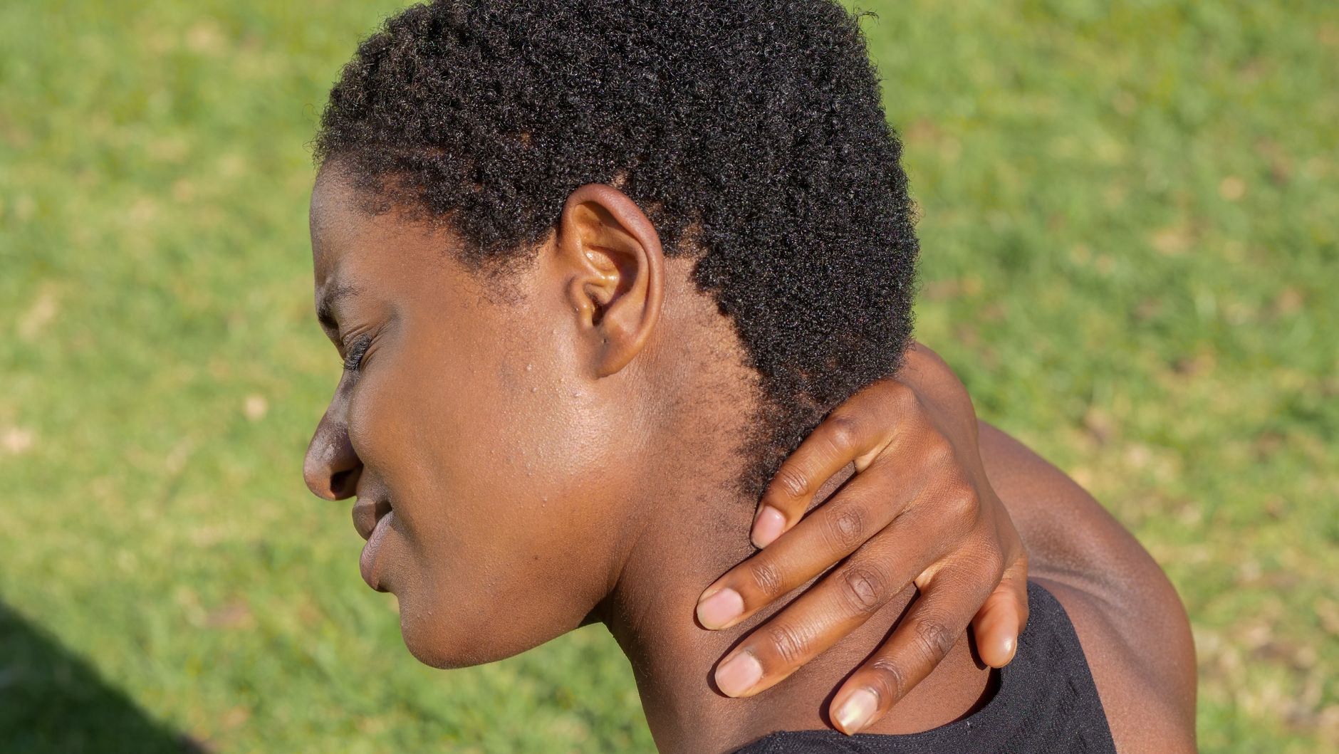 Woman with closed eyes gently touches her neck, suggesting release or comfort