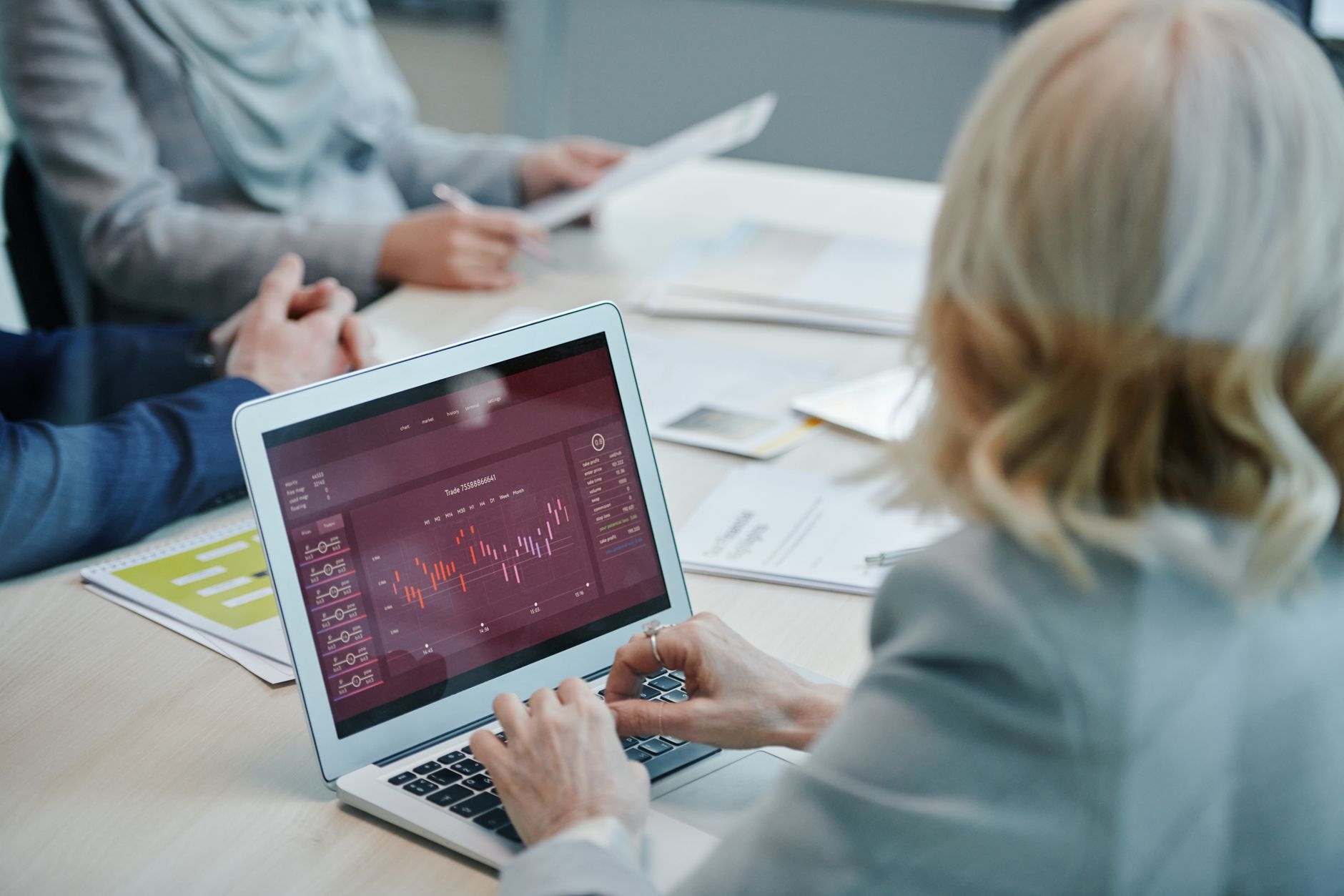Business professionals analyze financial charts on a laptop during a team meeting