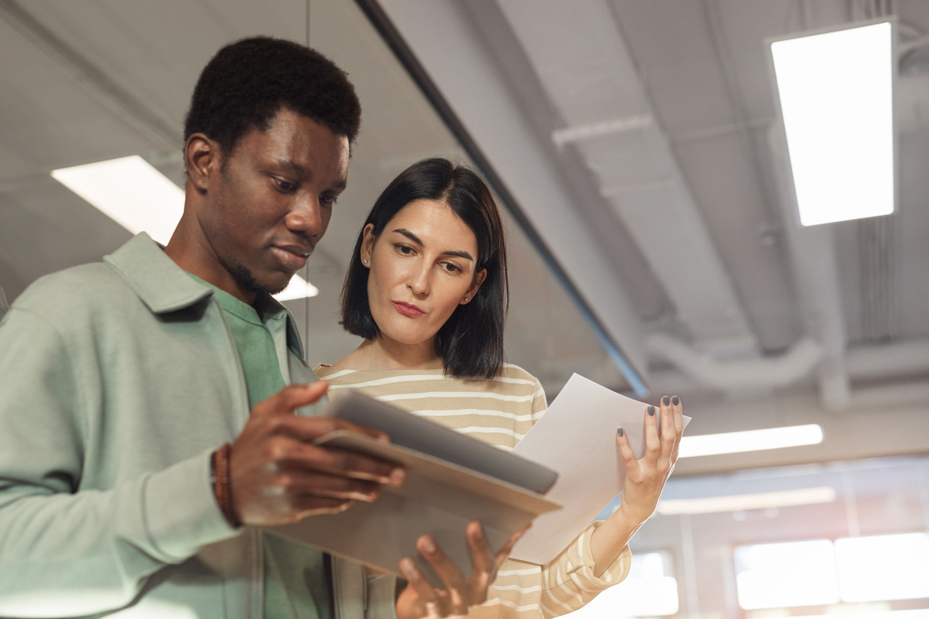 Two coworkers review automated SEO content performance and pricing on a digital tablet