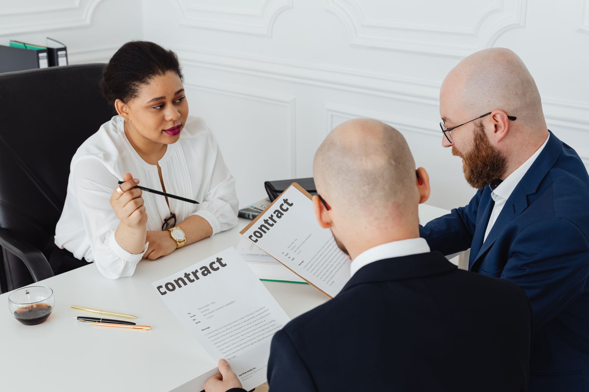 Lawyers and a businesswoman review commercial contracts during a dispute arbitration meeting