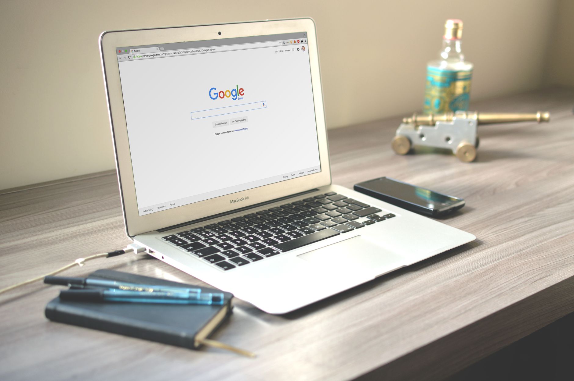 Laptop displaying the Google search page on a desk with a smartphone and notebook