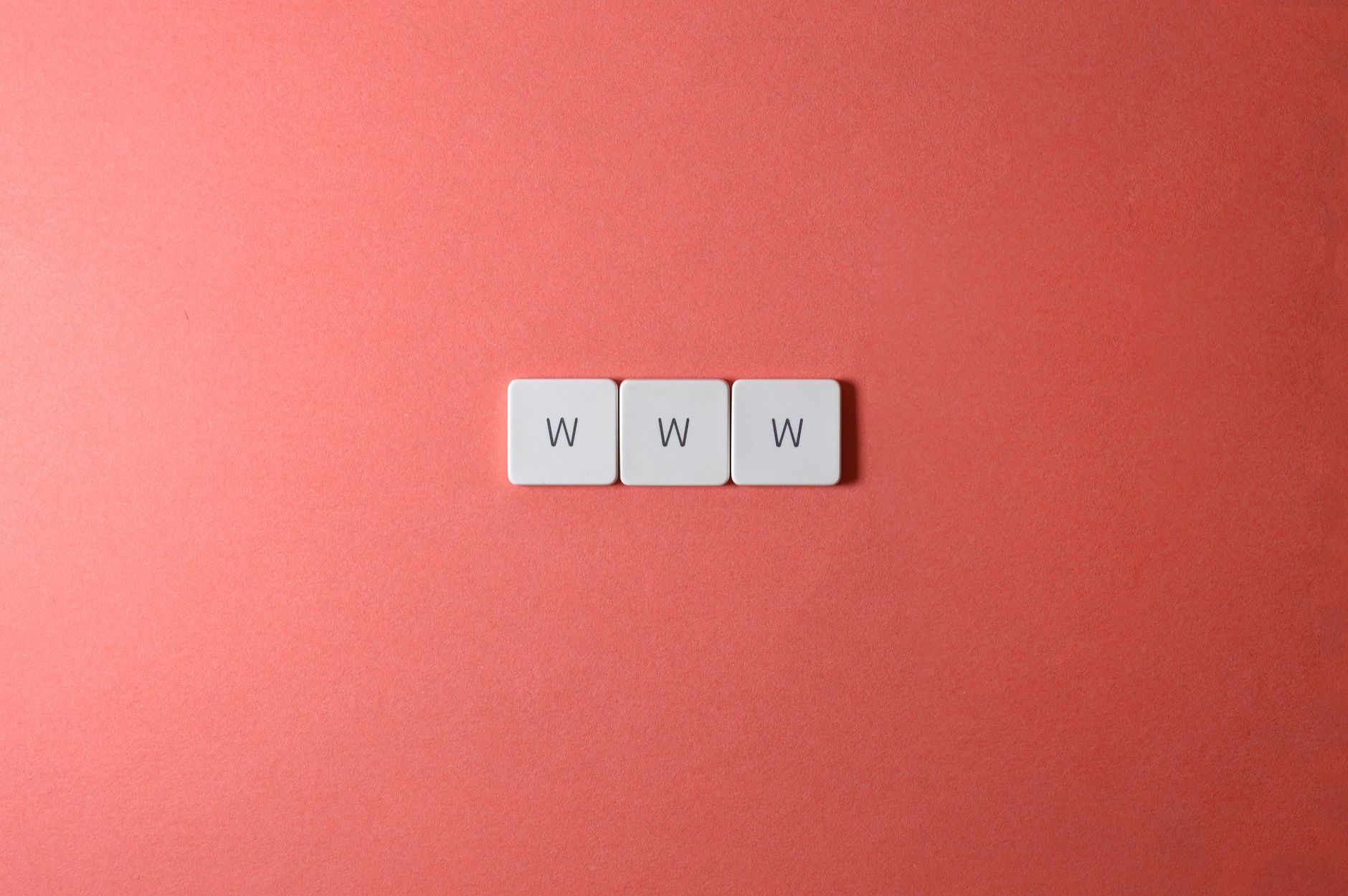Three white tiles spelling WWW on a coral background for a website address