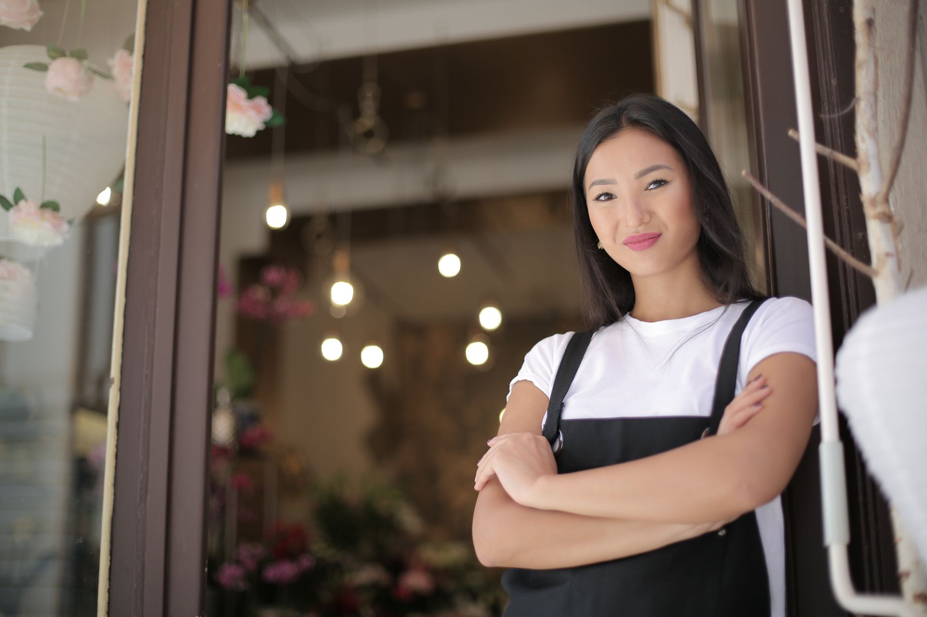 Smiling small business owner in an apron stands confidently at her shop entrance