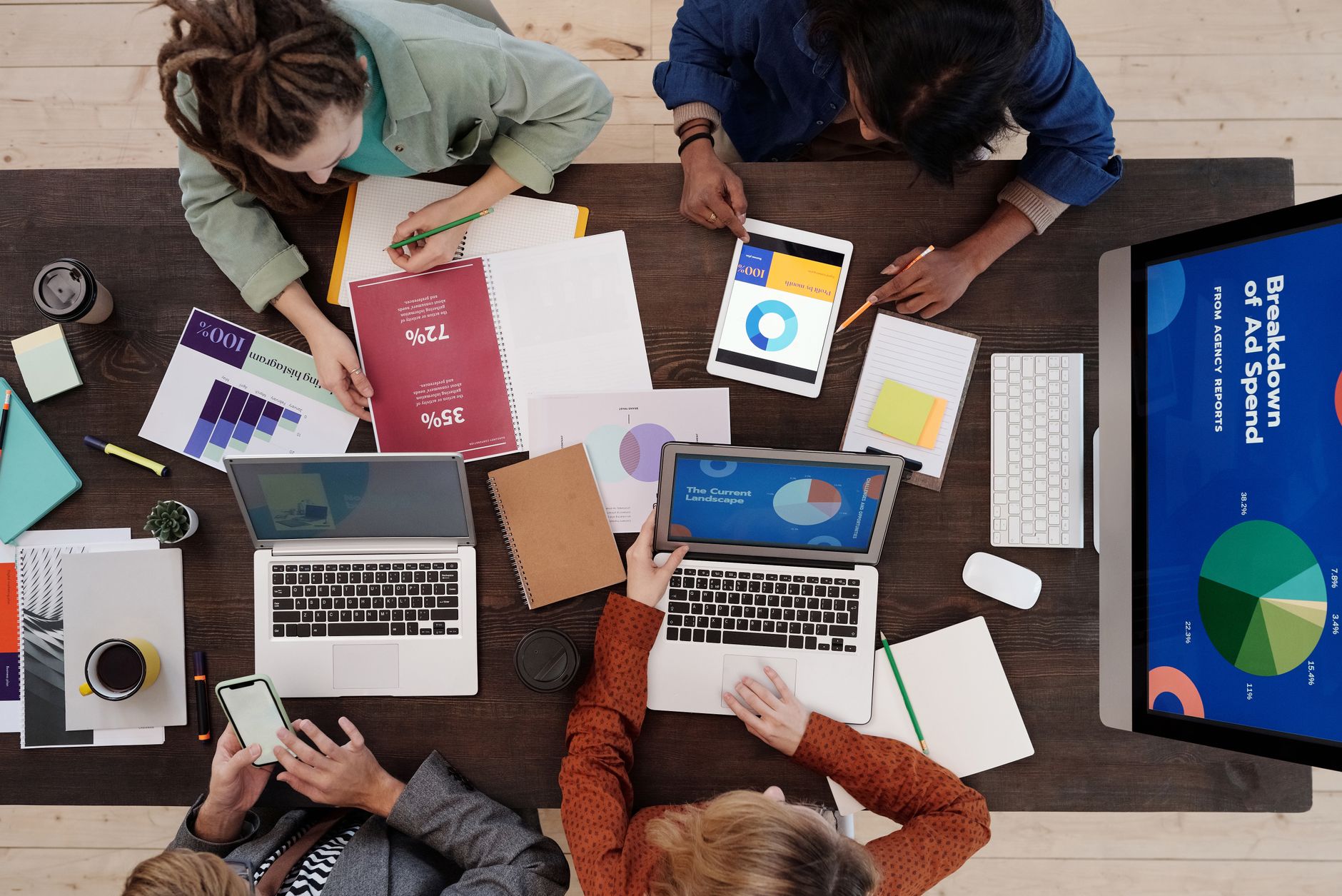 People reviewing digital and print reports on ad spend data at a table