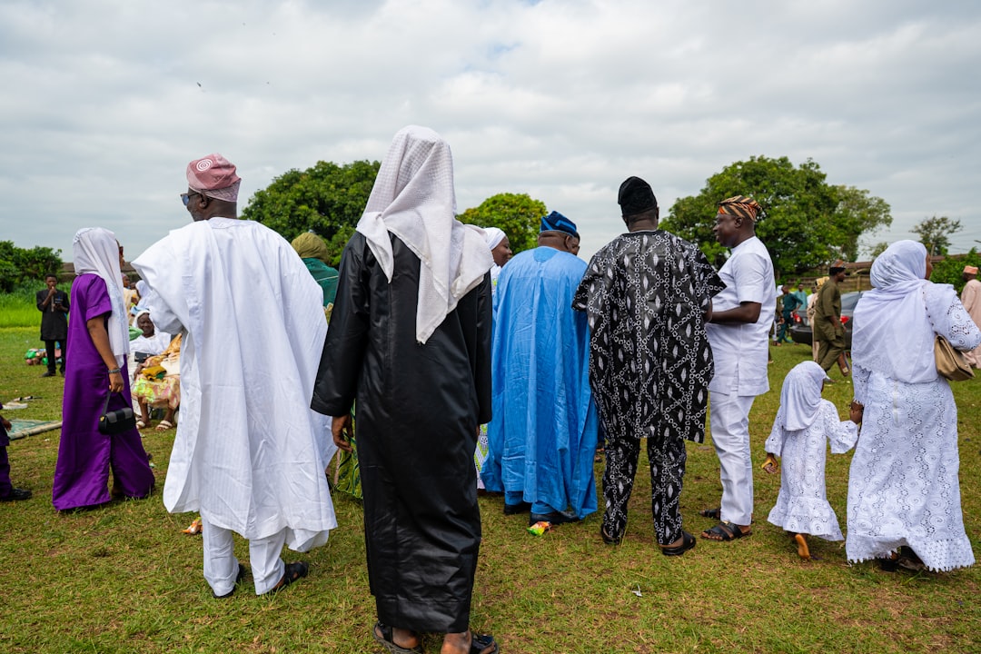 Group of people in traditional Nigerian attire standing outdoors on a grassy field