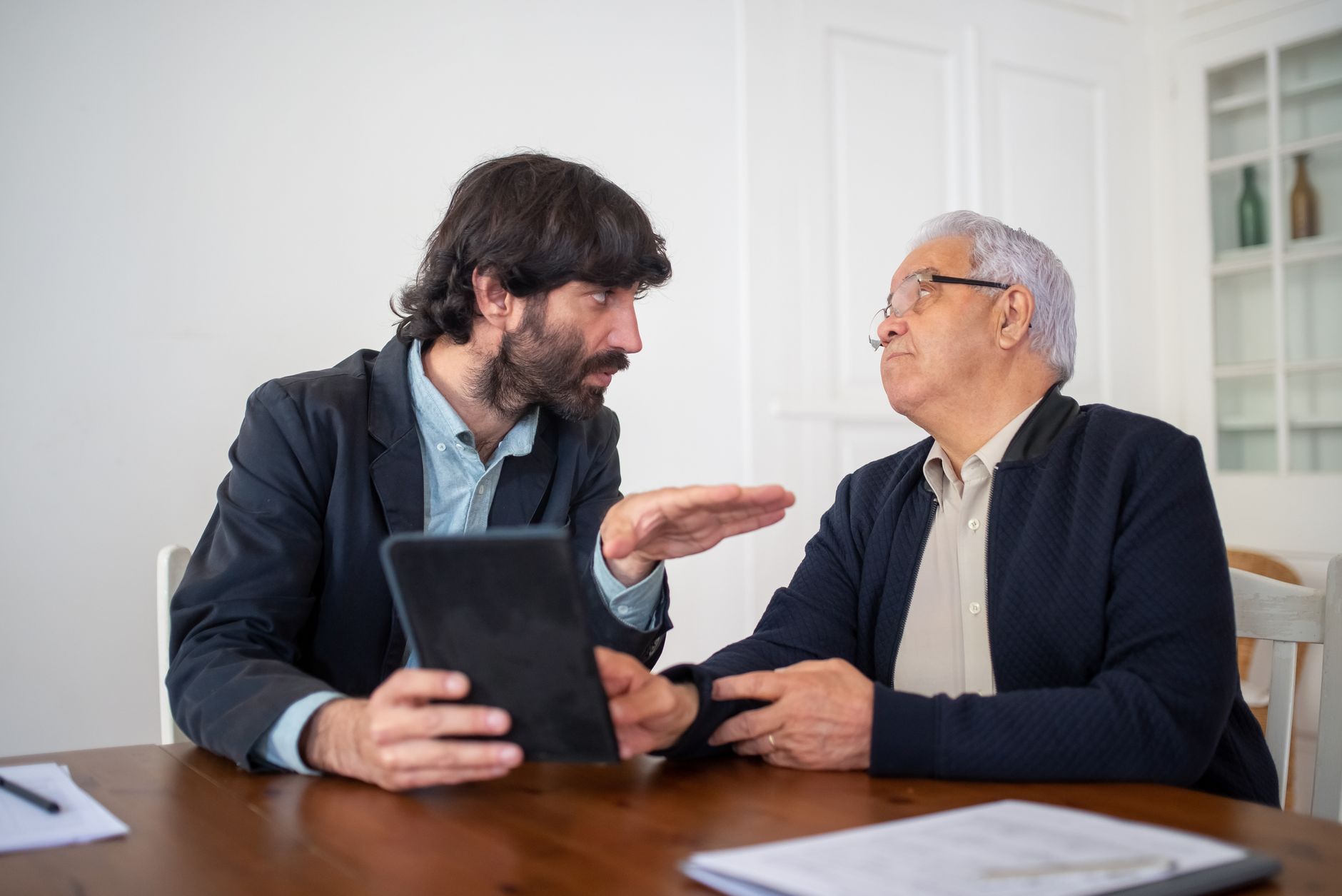 Two men discuss content expectations and budget limits across a table