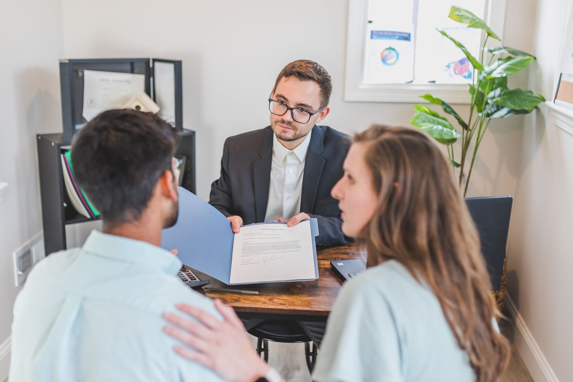 A professional shows a document in a blue folder to a couple