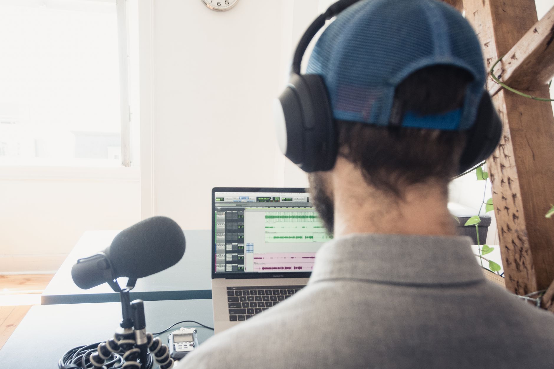 Podcaster editing audio on a laptop with a microphone in front