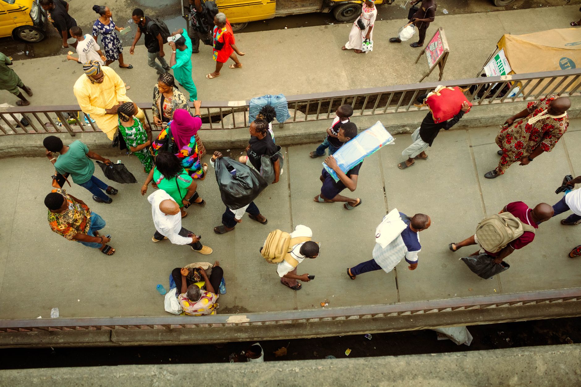 Overhead view of a bustling street with many pedestrians, some carrying goods