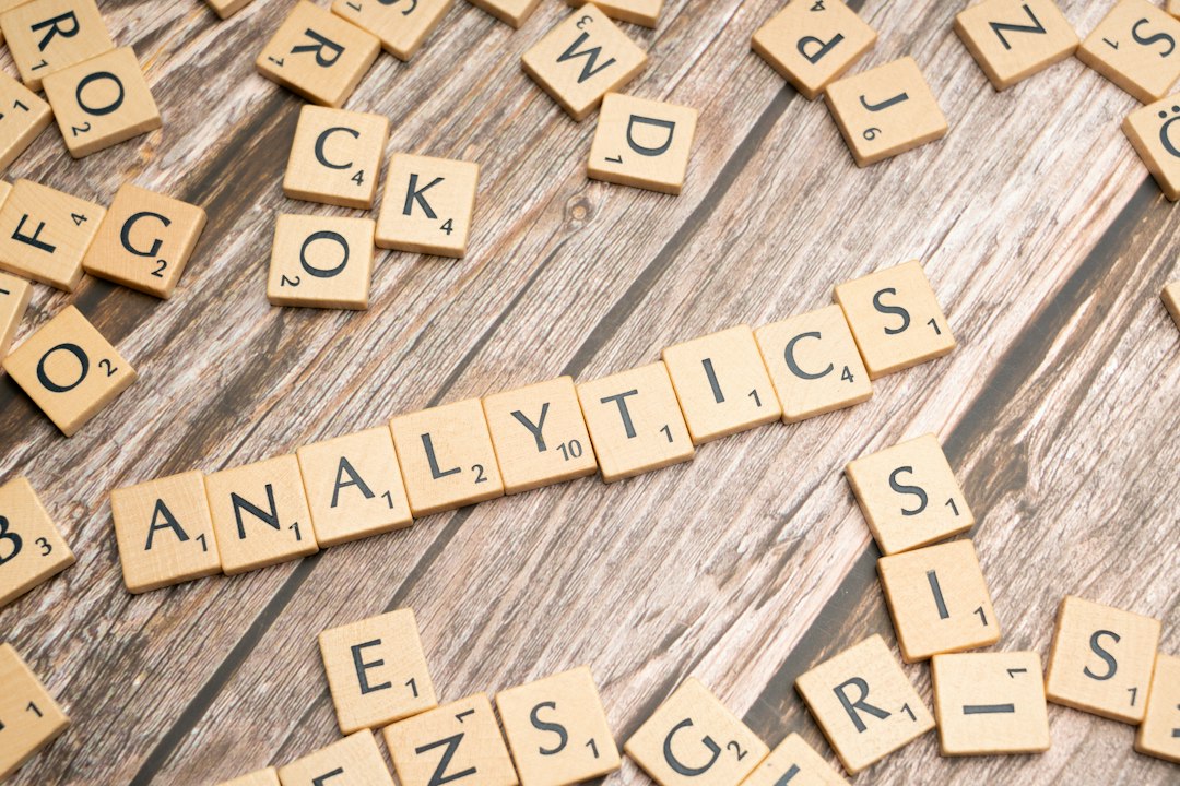 Scrabble tiles on wood spell "ANALYTICS" surrounded by scattered letters, suggesting data analysis