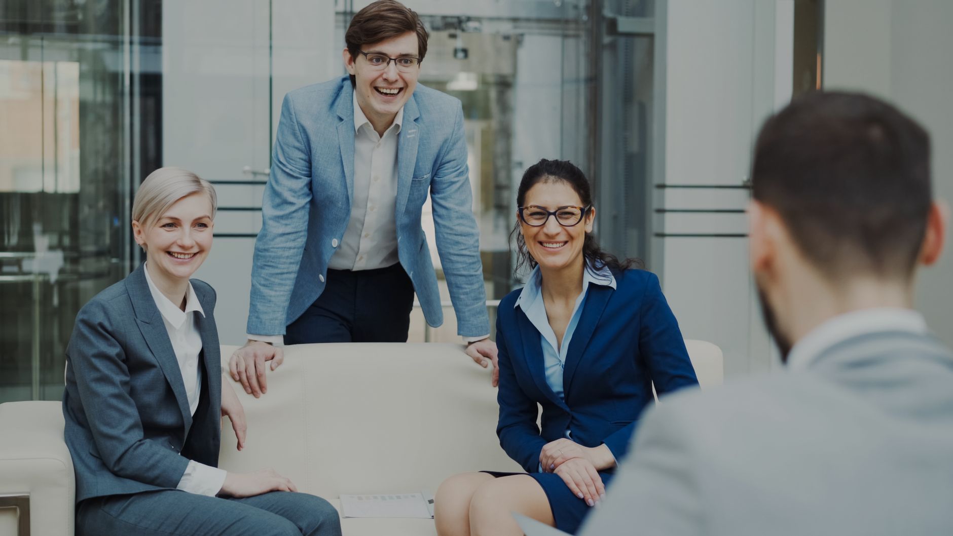 Smiling business professionals in suits and glasses meeting in a modern office space
