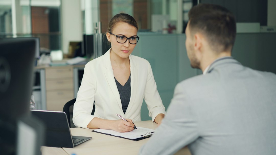 Woman interviewer taking notes while talking to a man in an office setting
