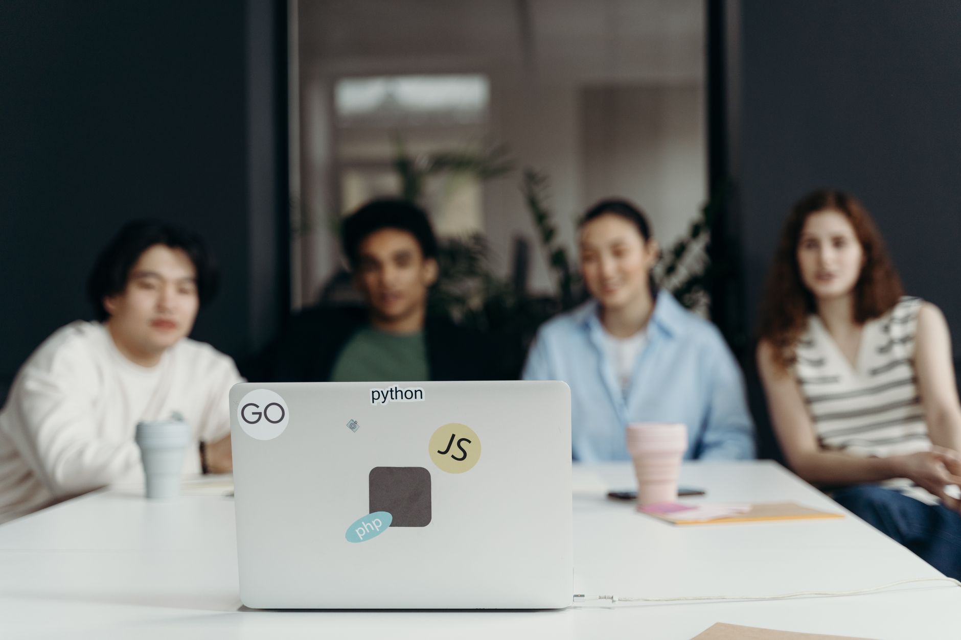 A laptop with programming language stickers in front of a diverse development team