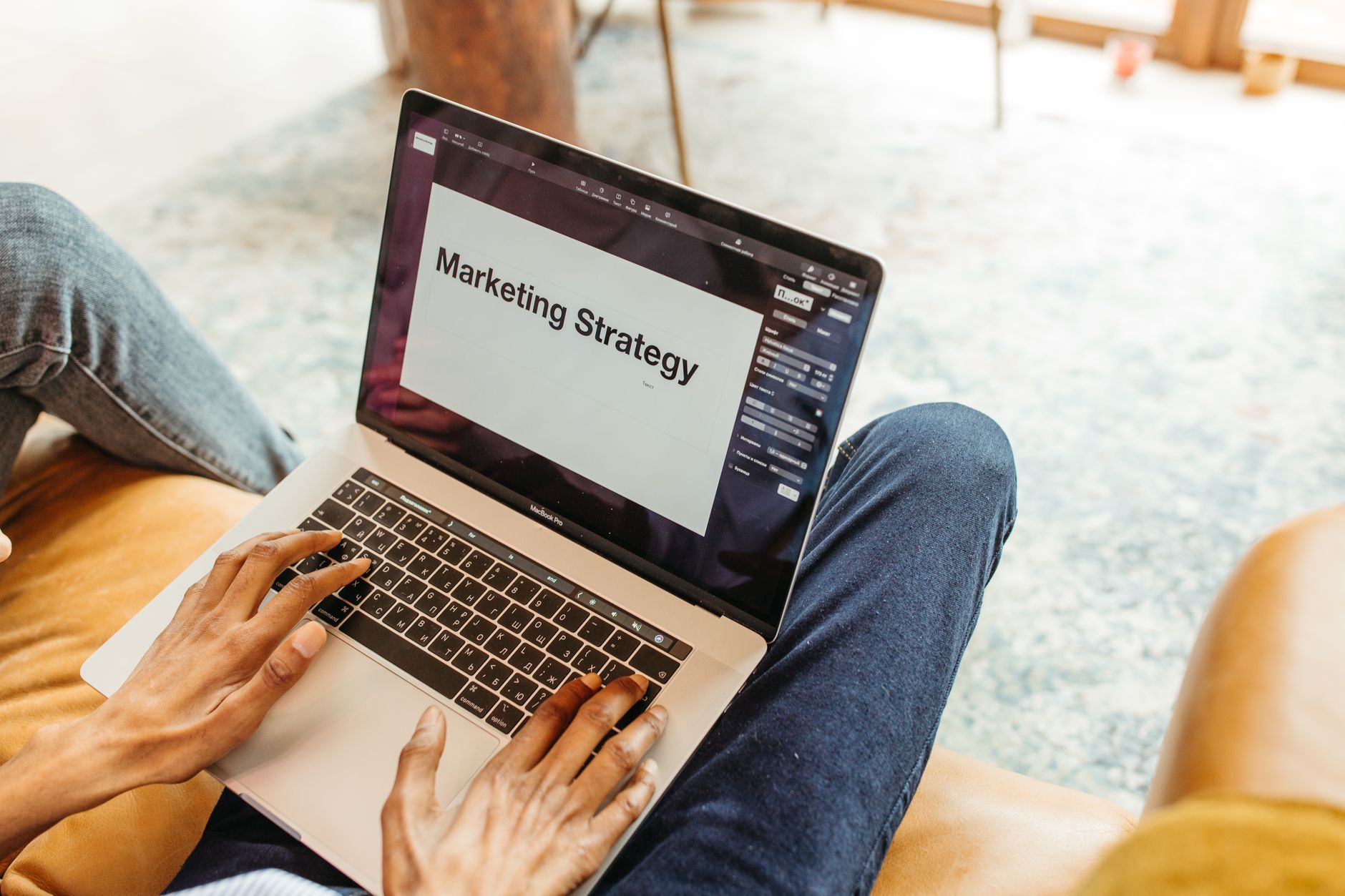 A person types on a laptop displaying Marketing Strategy on the screen
