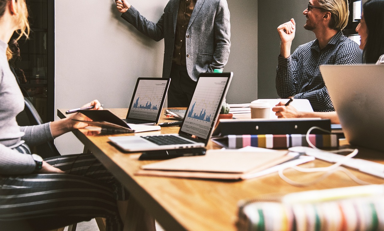 A team discusses change management with laptops displaying data charts in a meeting