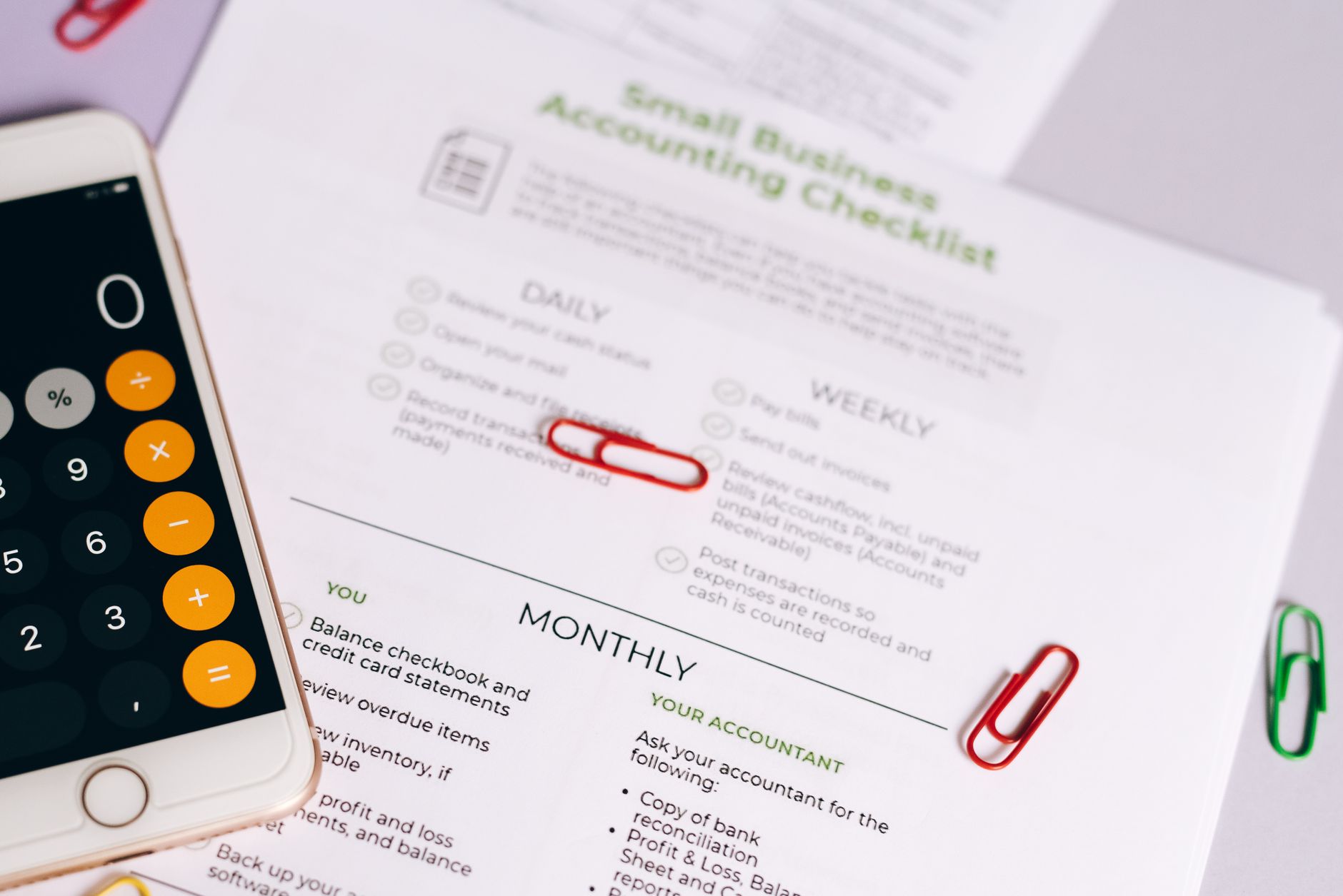 A phone calculator and an accounting checklist for managing business expenses