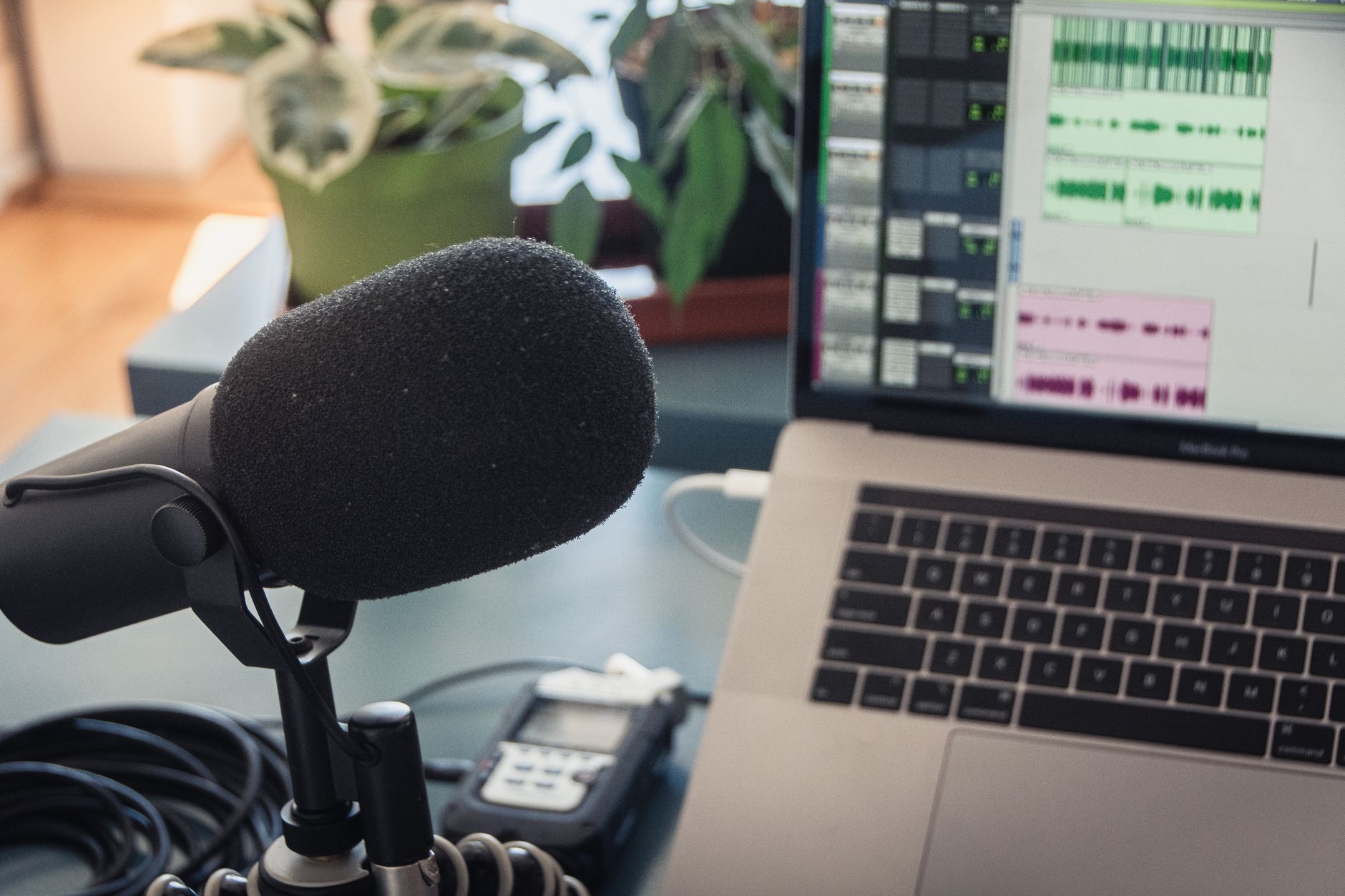 A microphone and laptop displaying audio editing software for podcast production