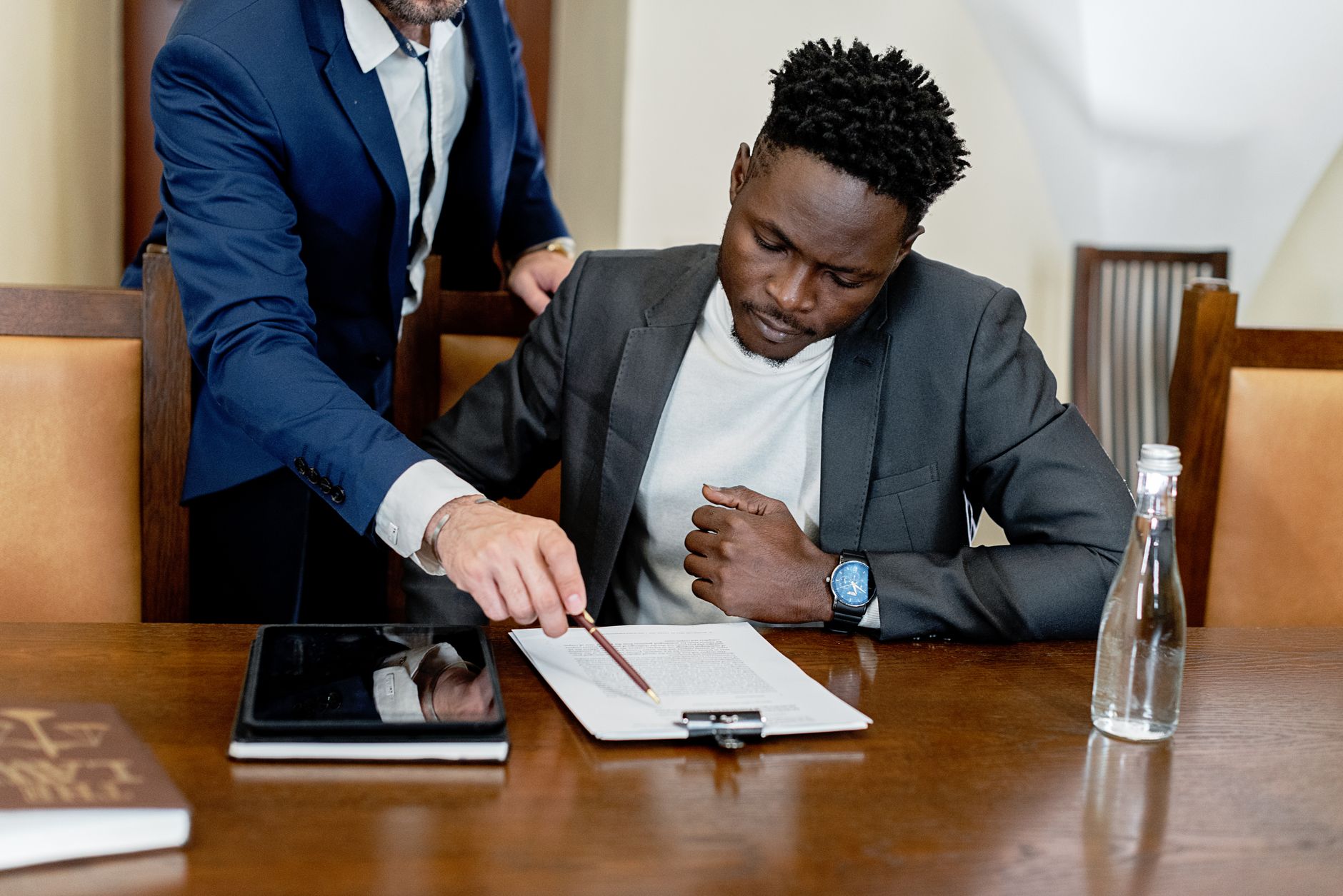 Two men reviewing a legal document on a wooden table