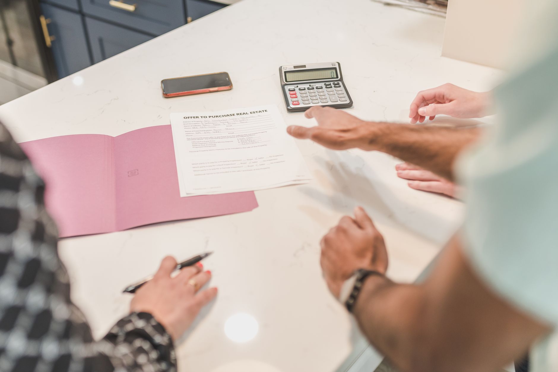 People reviewing an Offer to Purchase Real Estate document with a calculator nearby