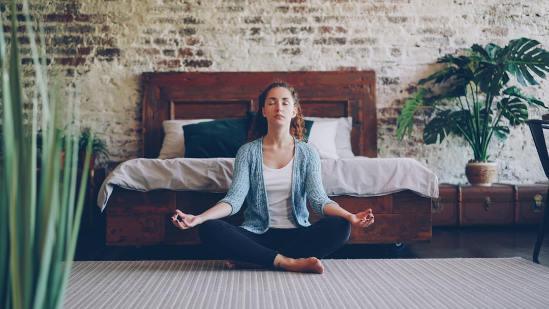 Young woman meditating on the floor in a bedroom, eyes closed, calm expression