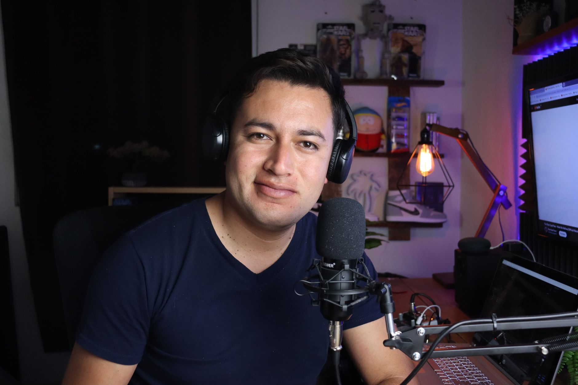 Smiling man with headphones and a microphone records a podcast in a home studio