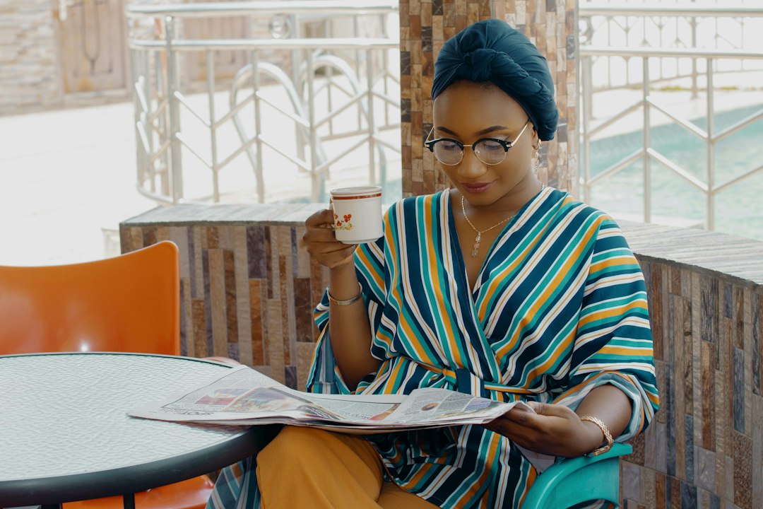 Woman in striped attire reading newspaper with a cup of coffee, considering legal documents