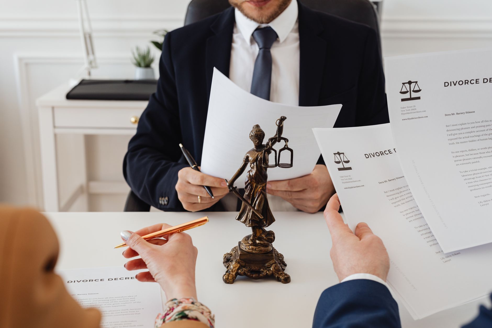 People reviewing divorce decrees with a lawyer and a Lady Justice statue