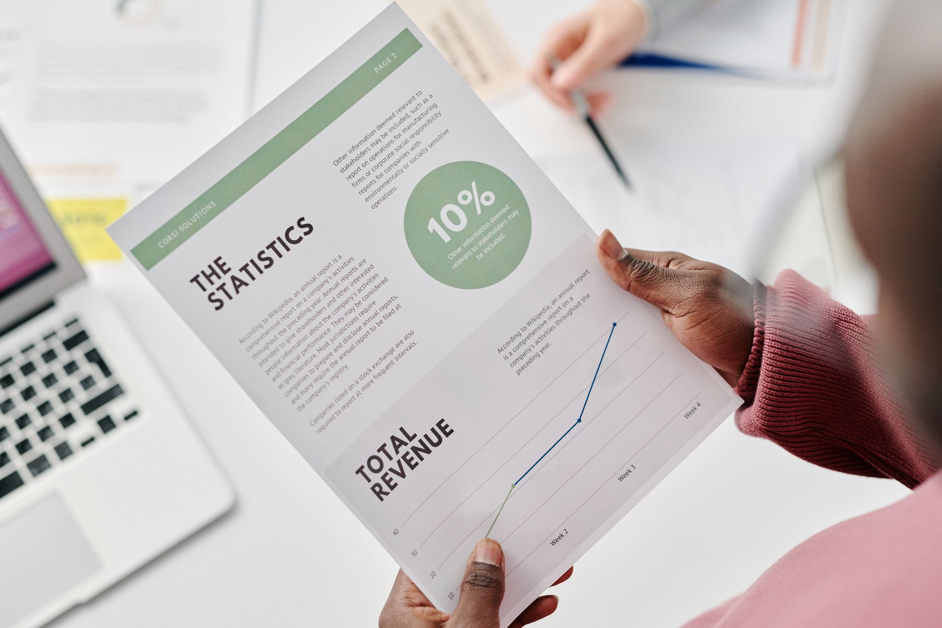 Person holding a financial report showing statistics, total revenue, and a 10% figure