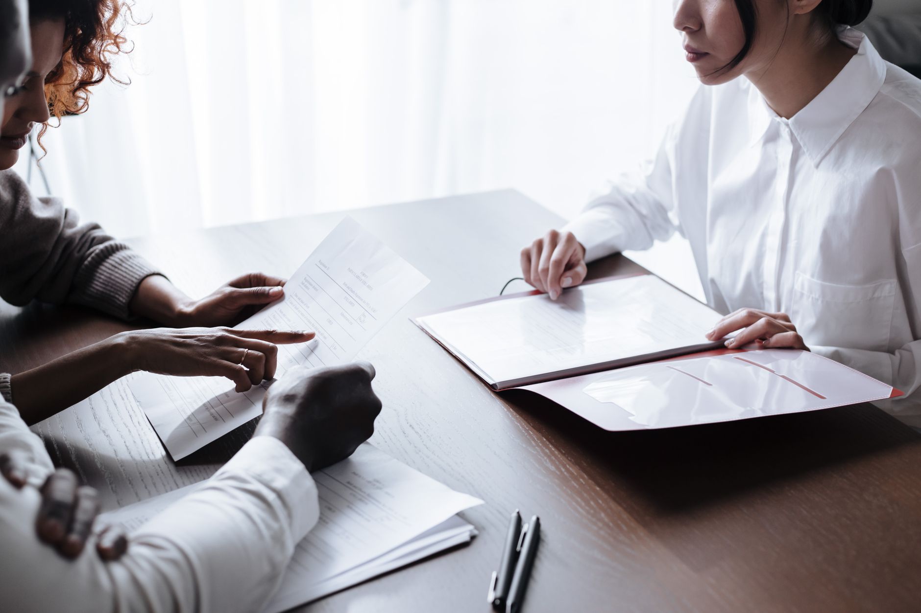 Three people reviewing documents at a table, discussing property acquisition