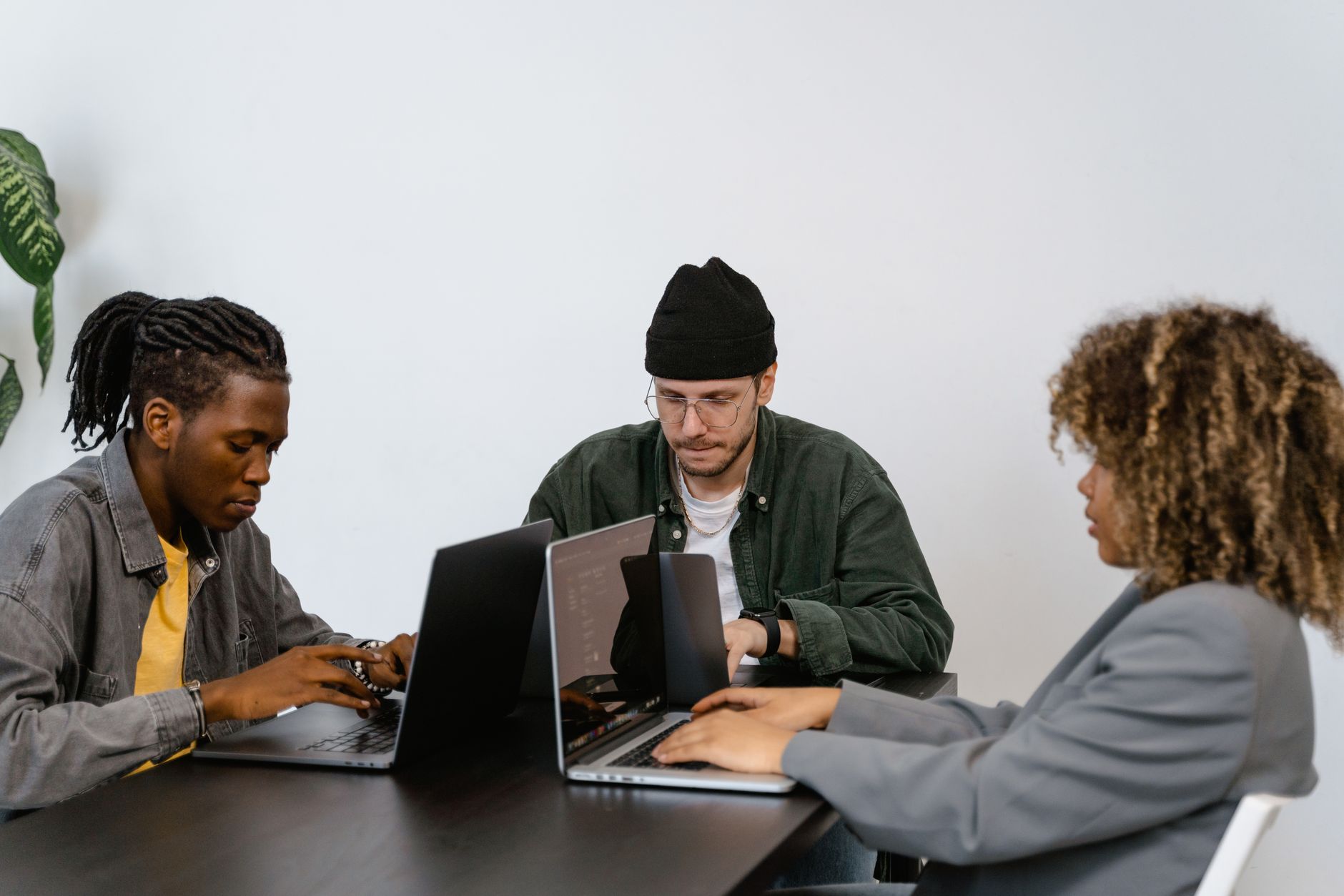 Three people sit at a table, using laptops to work on ranking methodology