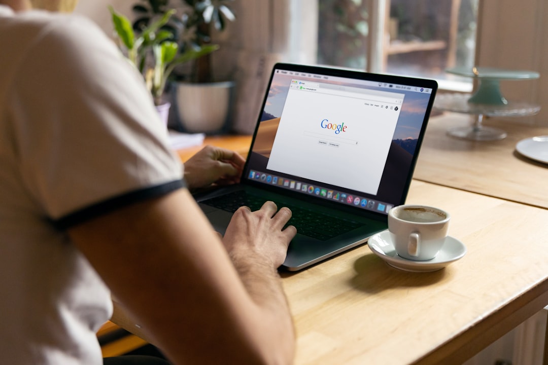 Person typing on a laptop displaying the Google search page and a coffee cup