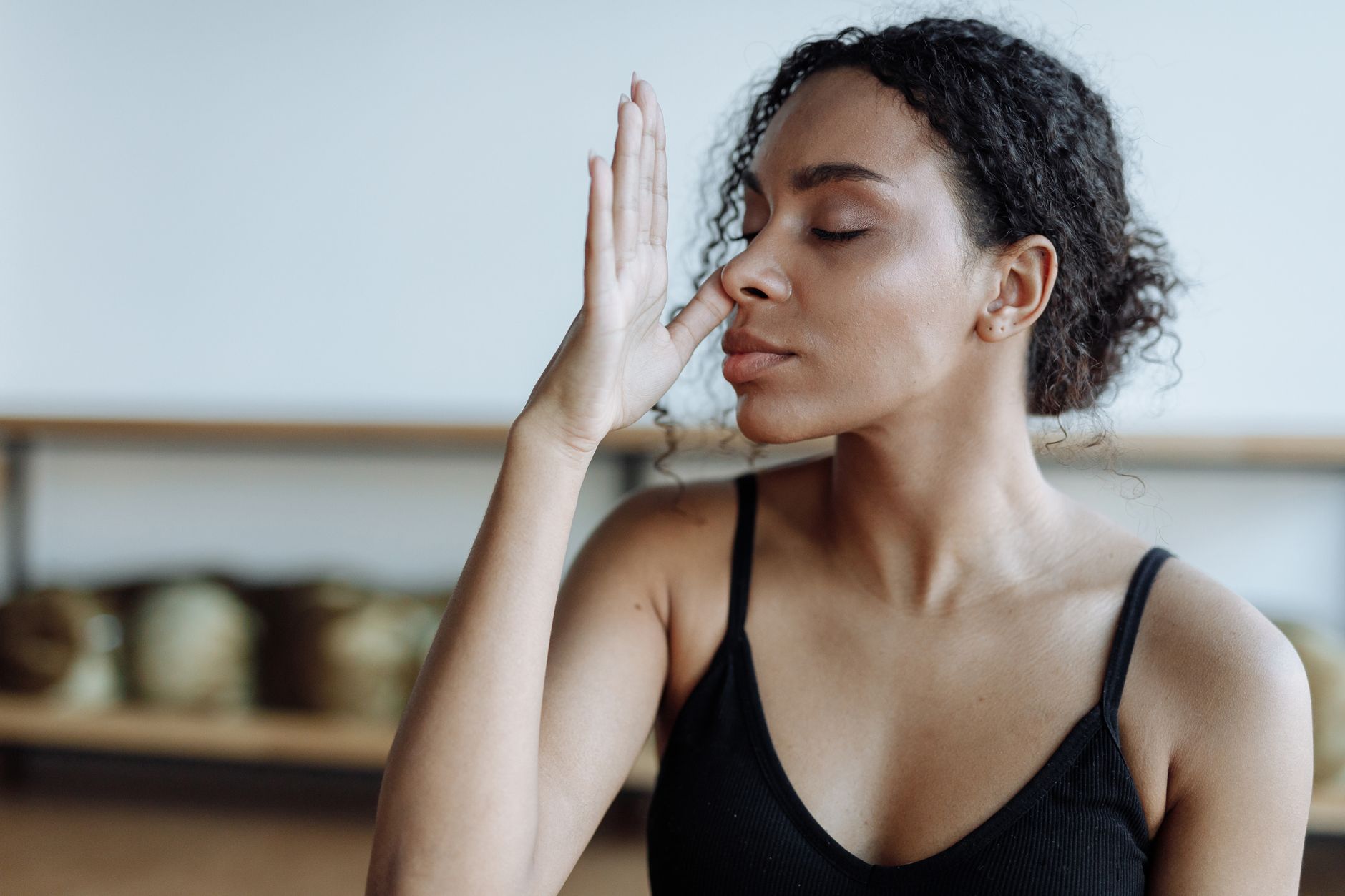 Woman with closed eyes performing alternate nostril breathing, likely at Asha's Place