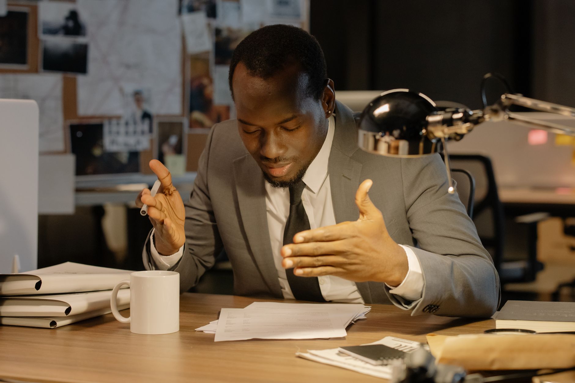 A man in a suit discusses documents at a desk under a lamp