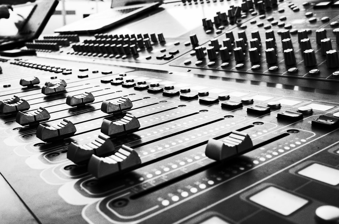 Black and white close-up of a complex professional audio mixing console with many faders