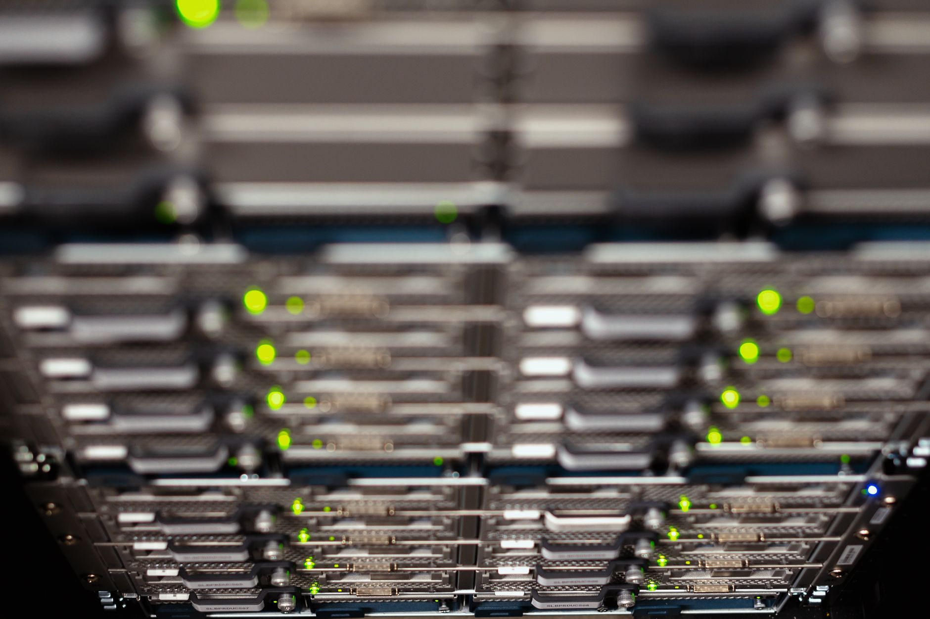 Rows of mounted computer server blades with glowing green indicator lights