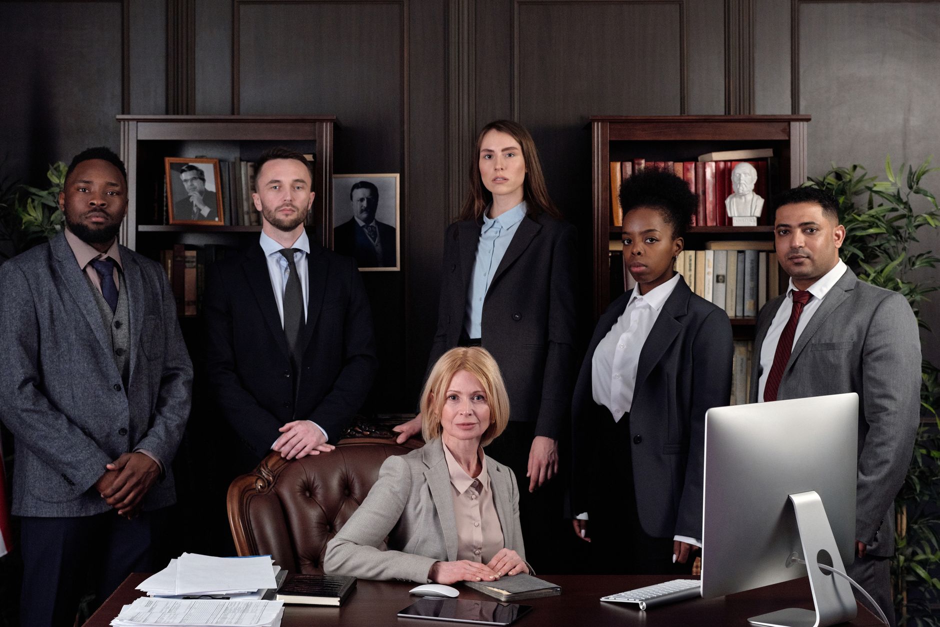 Diverse legal team of six professionals in suits within an office setting