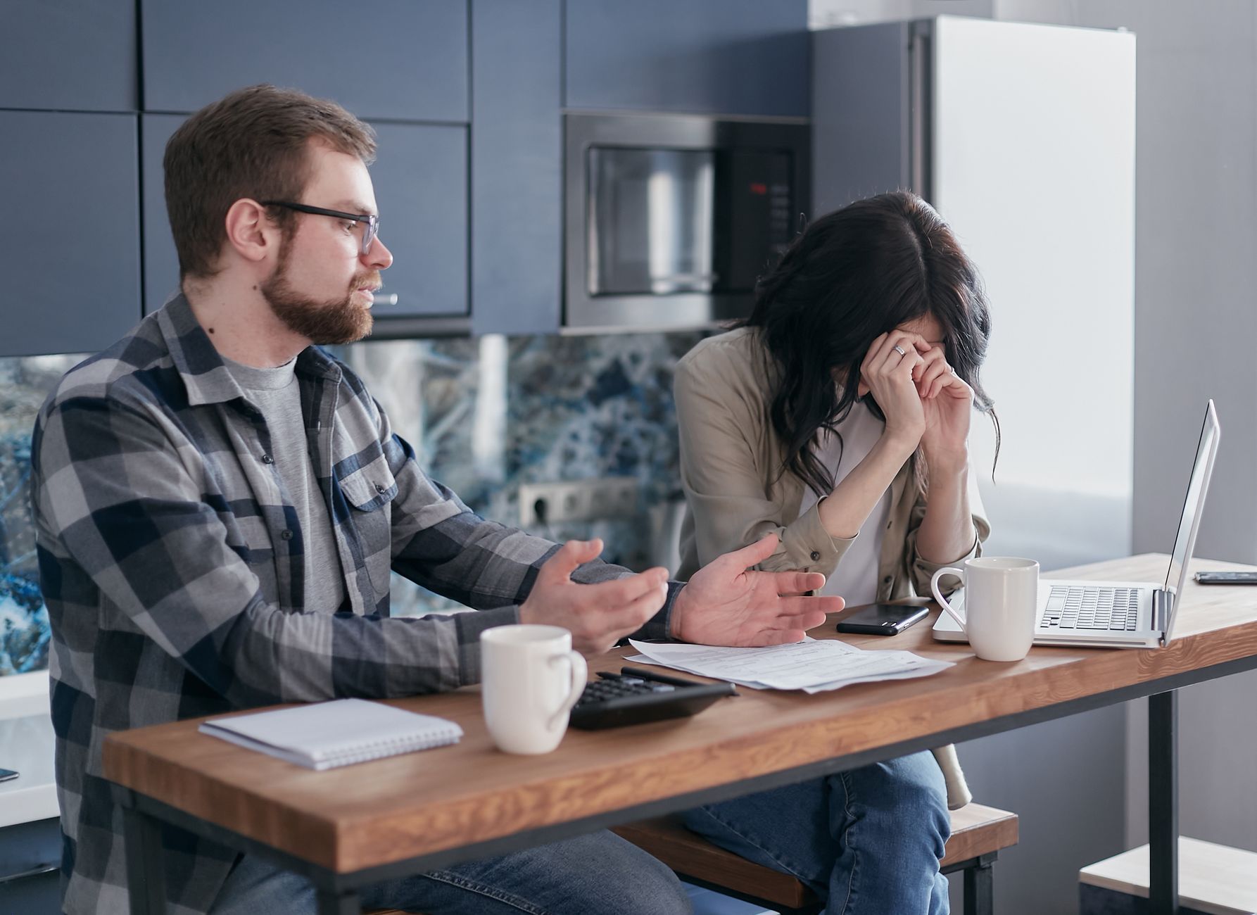 A man explains to a distressed woman at a table with papers