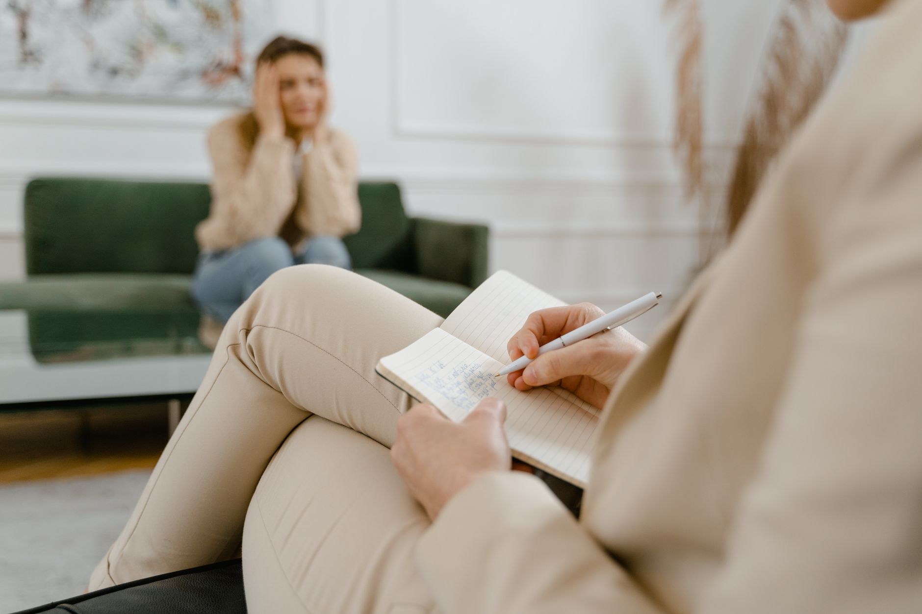 Therapist taking notes during a session with a distressed client on a couch