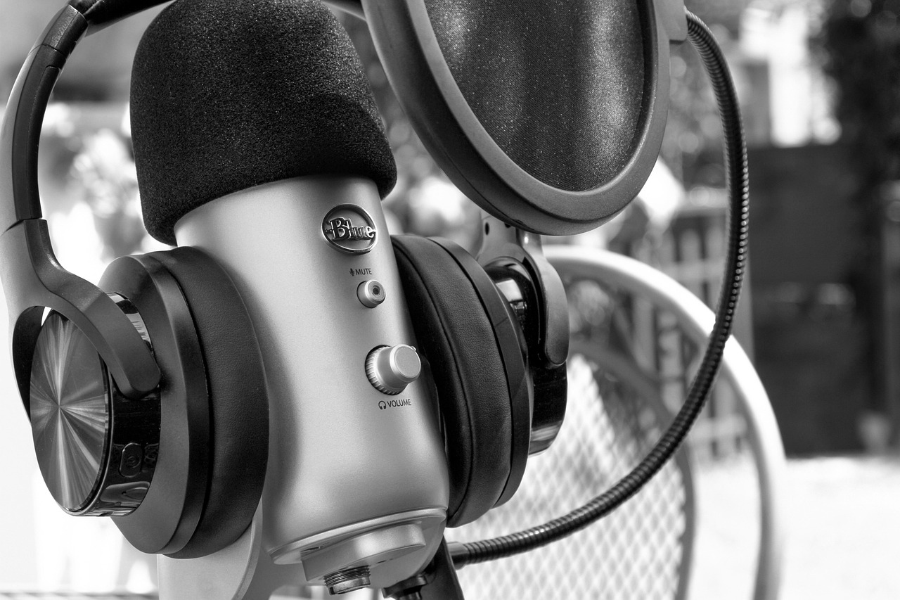 A close-up of a podcast microphone, headphones, and pop filter for recording