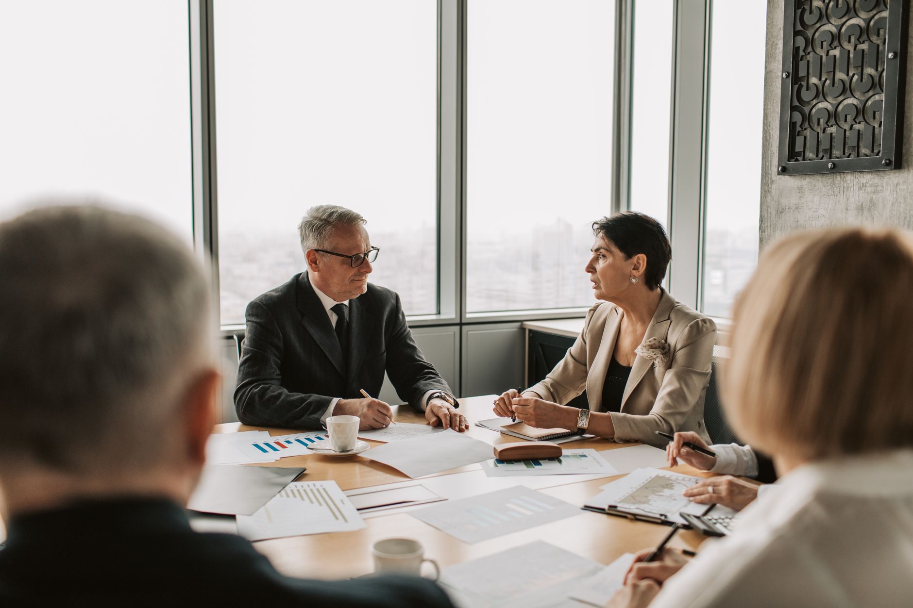 Business professionals consult at a table with charts in a modern office