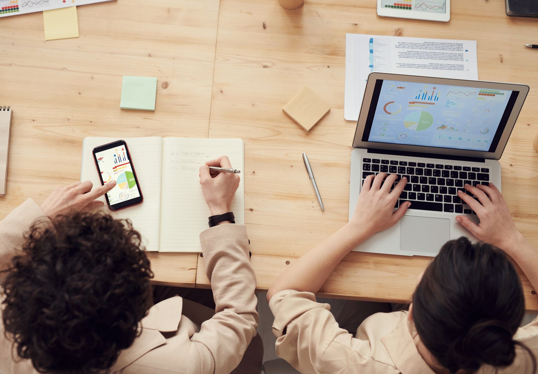 Two people using a laptop and phone to analyze data for programmatic SEO audits