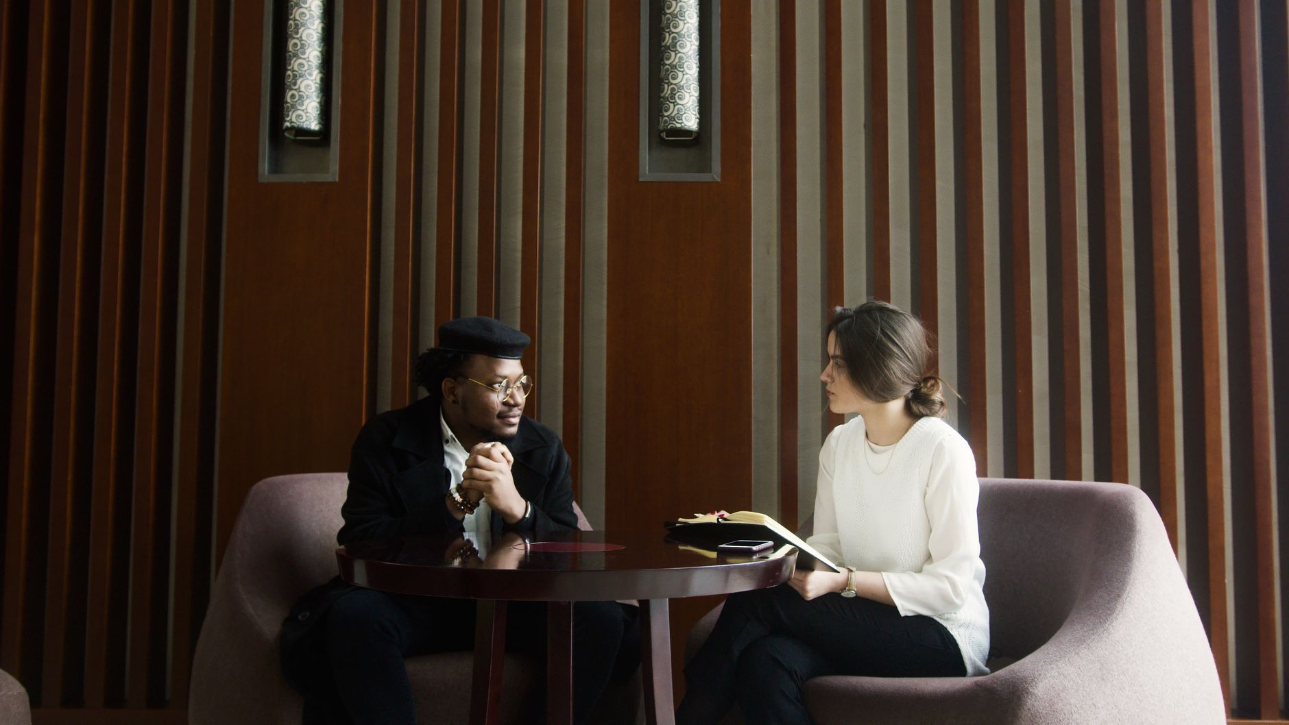 Two people discuss user research methods at a table in a modern setting