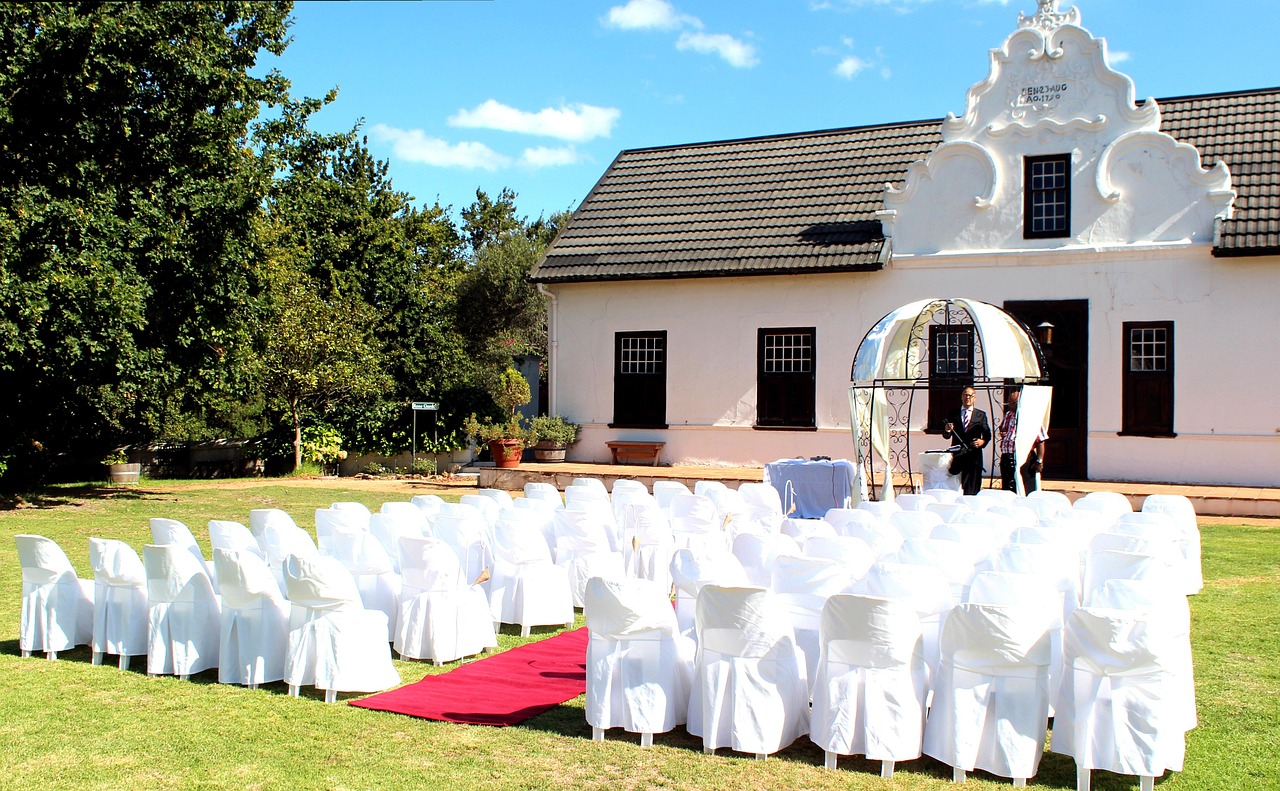 White covered chairs on a lawn with a red aisle in front of a white building