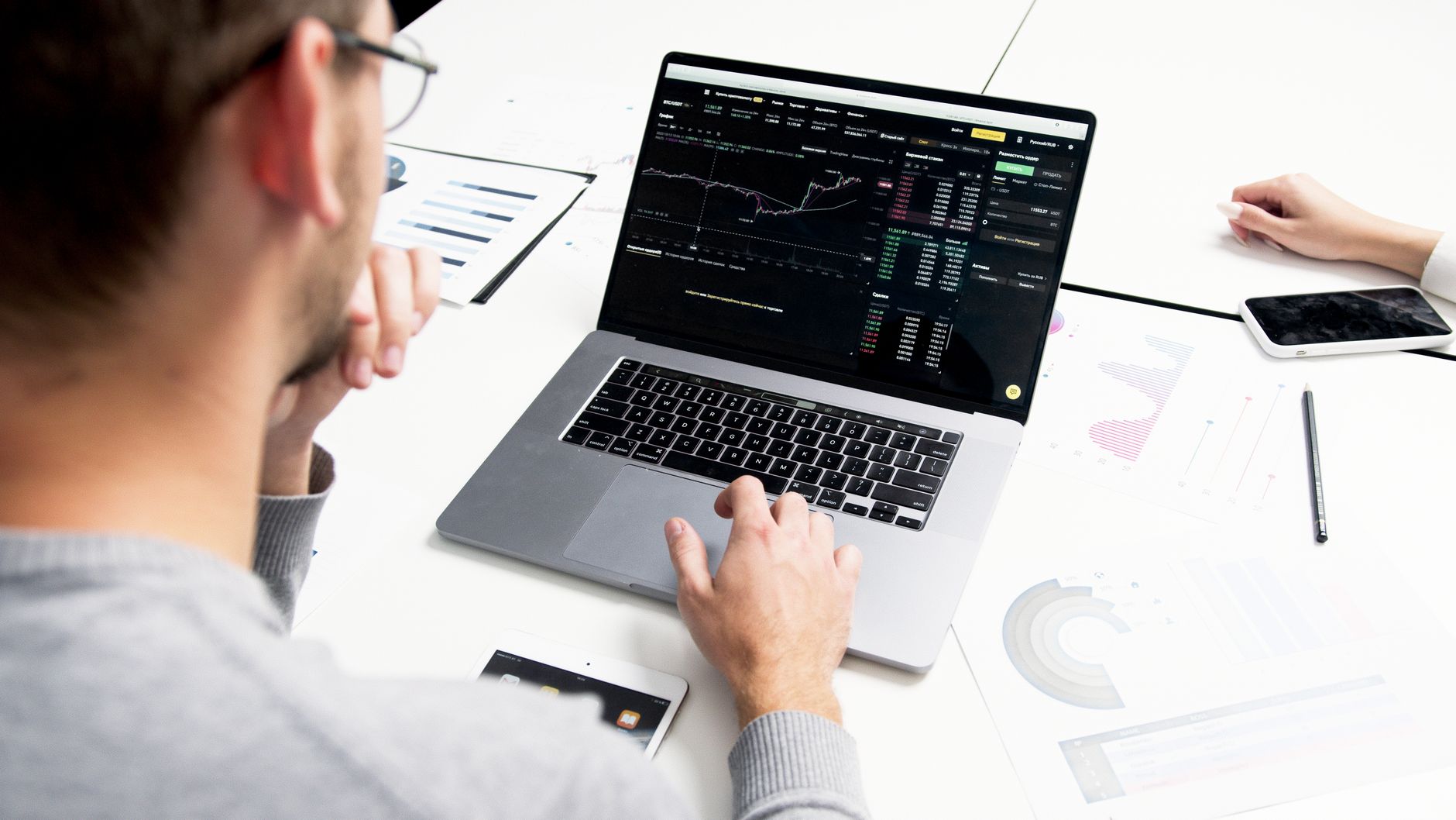 A person analyzes website analytics graphs and data on a laptop and papers