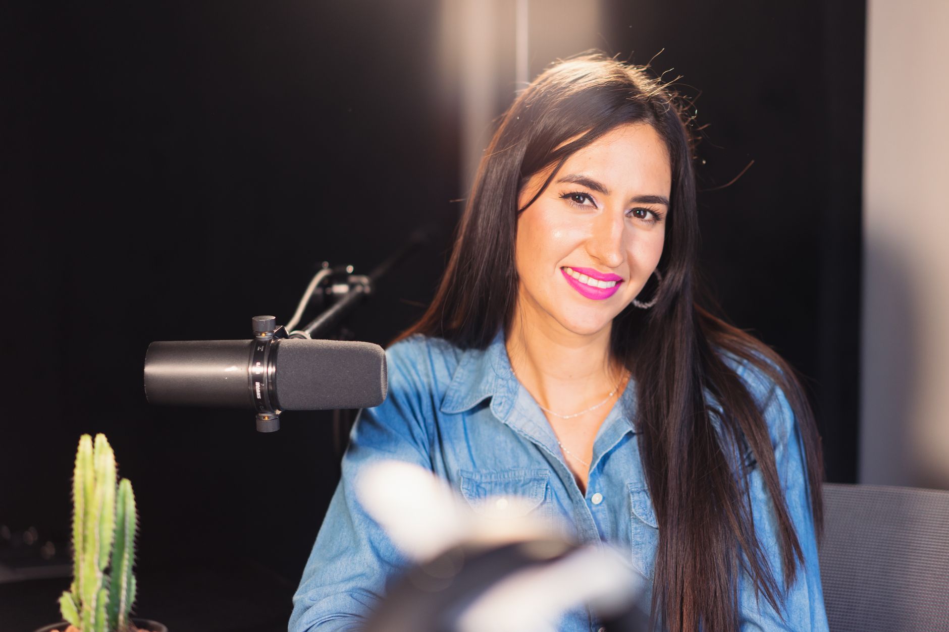 Smiling woman podcasting with a professional microphone in a studio setting