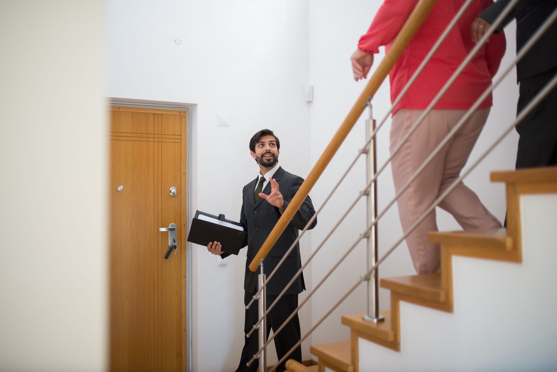 A man in a suit holding a folder talking to people on stairs inside a building