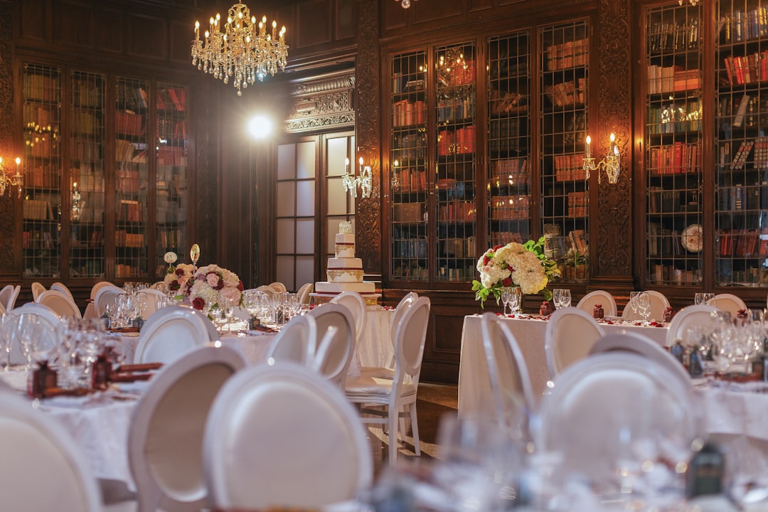 A lavish wedding reception set in a library with a grand cake and white chairs